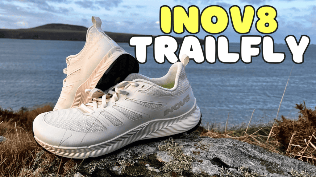 Photo of the Inov8 Trailfly in white on a mossy rock with the sea in the background and the caption saying Inov8 trailfly