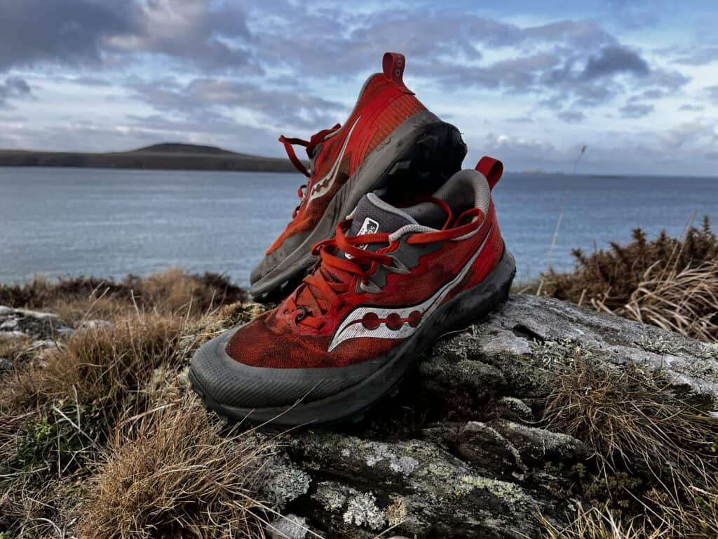 Picture of the saucony peregrine 14 in red on a mossy rock